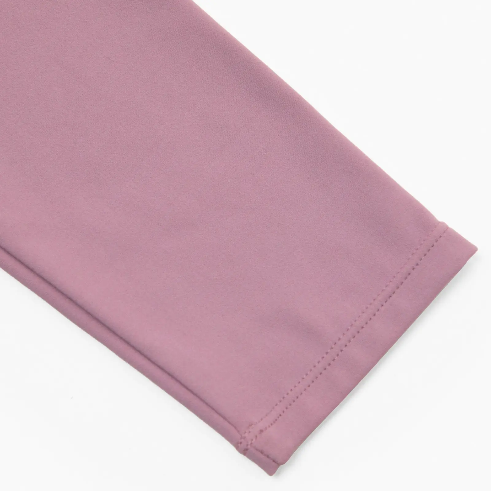 Close-up of light pink long sleeve bodysuit sleeve over a white background