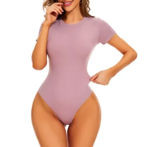 Caucasian woman posing and wearing a light pink t-shirt bodysuit with a white background.